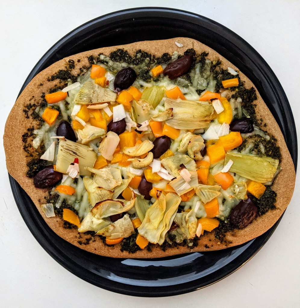 zesty pesto pizza with vegetables zesty pizza with basil pesto, artichokes, Kalamata olives, mozzarella cheese, peppers, garlic, and onions