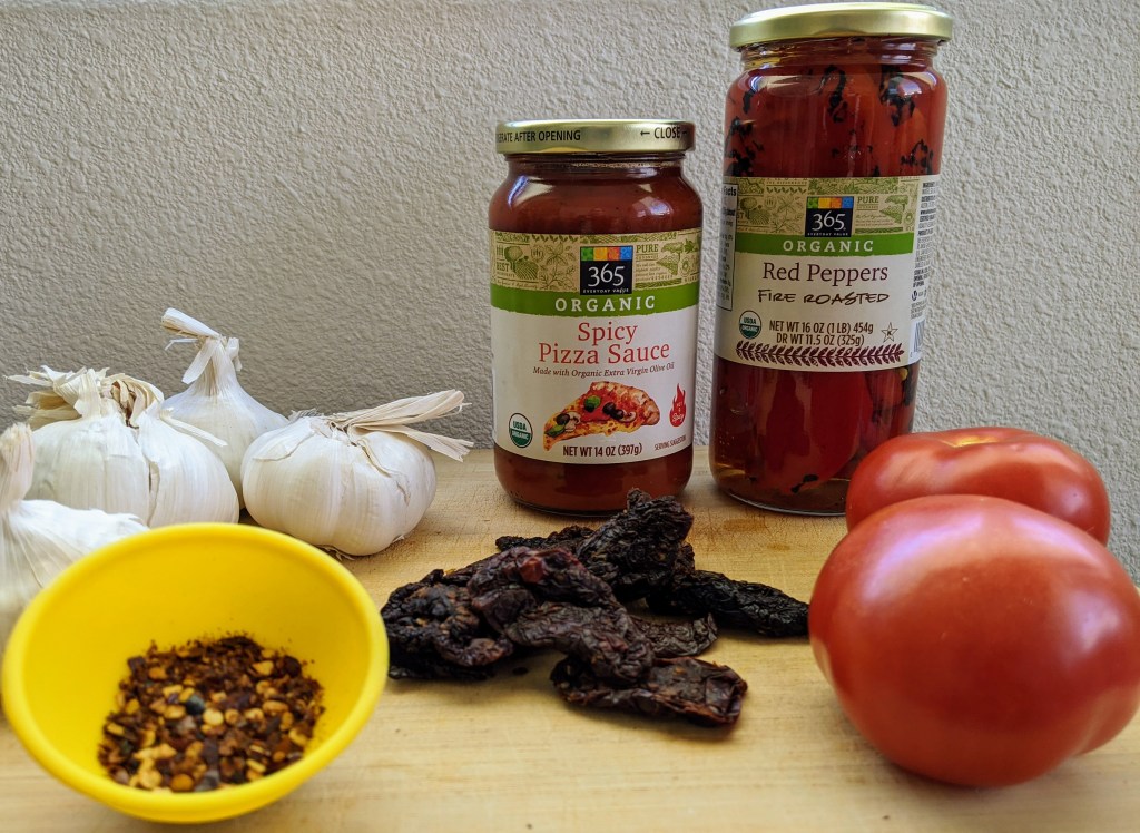 ingredients for the Il Diavolo pizza, garlic, tomatoes, sun dried tomatoes, red pepper flakes, red peppers, and spicy pizza sauce