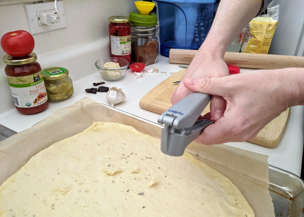crushing garlic over the pizza base